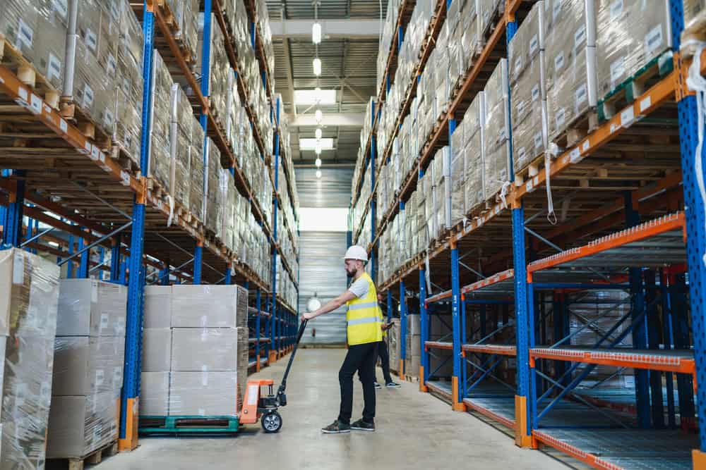 a man moving boxes in a huge warehouse